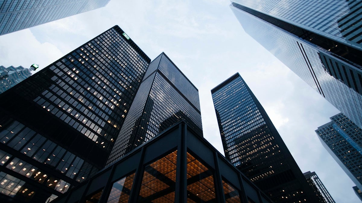 Vista aérea de um porto movimentado com navios de carga e contêineres, simbolizando comércio internacional e logística